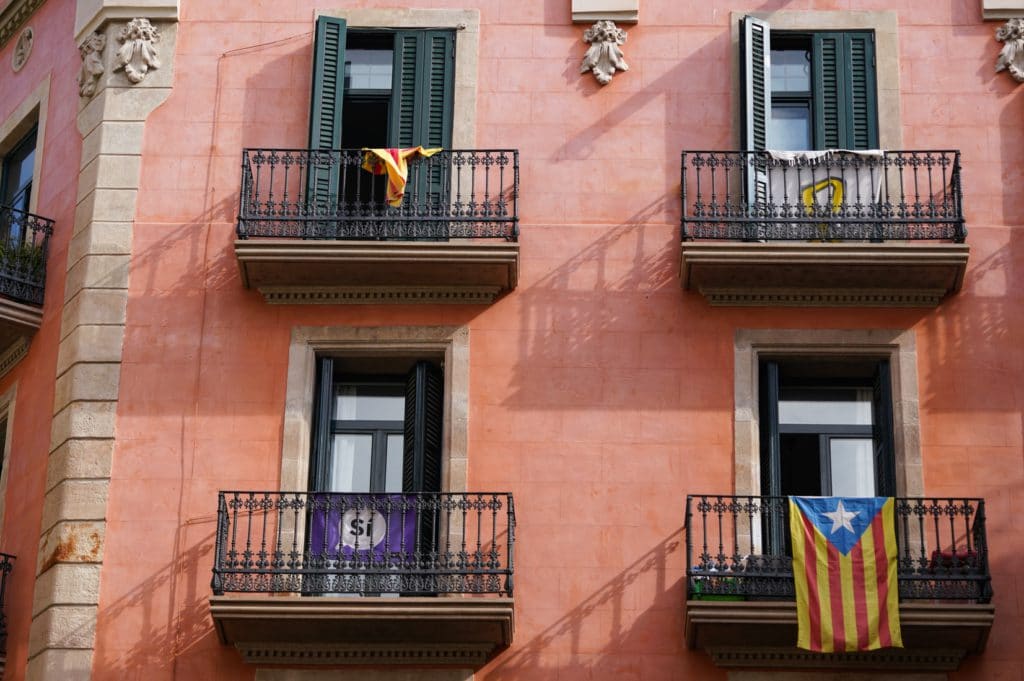 Vivre et travailler depuis Barcelone : devanture de maison rose avec drapeaux espagnols à la fenêtre