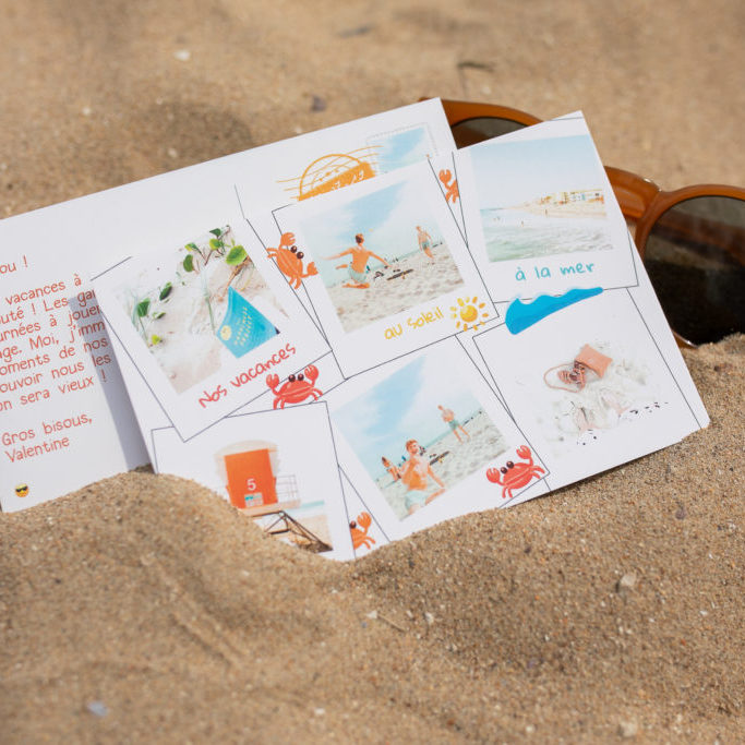 carte postale vacances posee dans sable avec lunettes