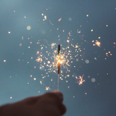 hand holding a sparkler in the sky