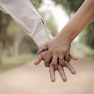 couple holding hands with engagement ring
