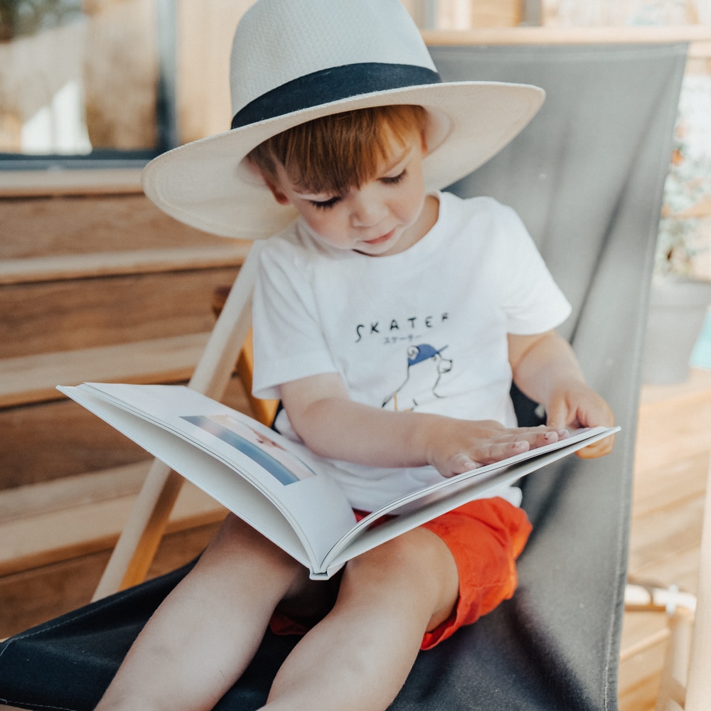 enfant avec chapeau lisant un album photo
