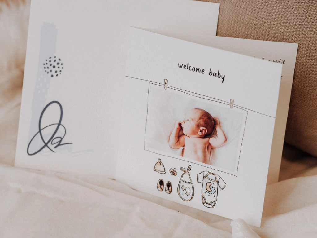 announcement card with baby clothes saying welcome baby