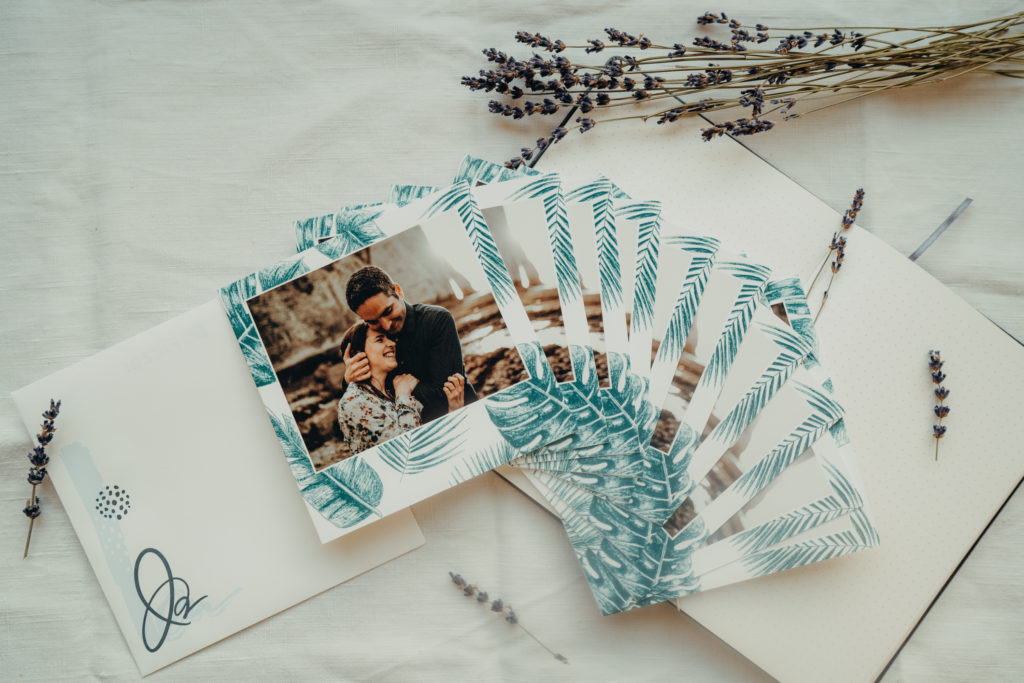 stack of wedding invitations with couple and monstera leaves