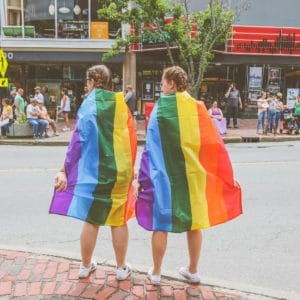 Zwei Frauen tragen eine Regenbogenfahne für Gay Pride.