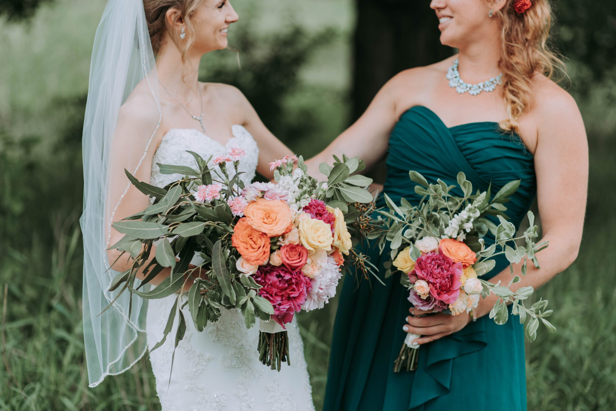 mariée avec sa témoin de mariage tenant des bouquets de fleurs colorées